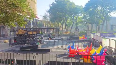 Parlak oyuncaklarla dolu renkli bir şehir parkı sabah güneşinin altında ağaçlar ve çitlerle çevrili boş duruyor..
