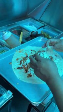 Büyük bir tortilla, taco arabasında hazır bir tepside bir satıcı tarafından pirinç ve etle doldurulur..