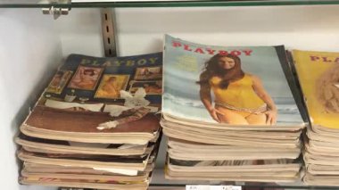  Aşınmış kenarları ve ikonik kapak modelleri olan bir yığın eski Playboy dergisi bir ikinci el dükkanında ya da koleksiyon dükkanında rafta duruyor..