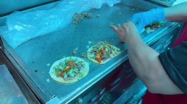 Eldivenli satıcı. Taco soslu taco ve tako hazırlama istasyonunda garnitür..