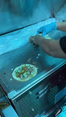 Bir taquero tacoları doğrudan tencerenin üzerine monte eder, spatula ve aletlerle tortilla üzerinde taze ızgara et hazırlar..