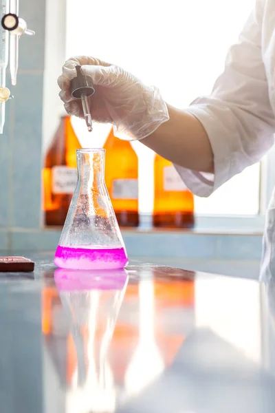 Chemistry expert is working with solutions and test tubes on the workbench in a chemistry laboratory. is a facility that provides controlled conditions in which scientific or technological research.