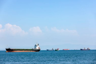 View of the cargo ship and transport for cargo (goods) with blue mediterranean sea and cloudy sky.