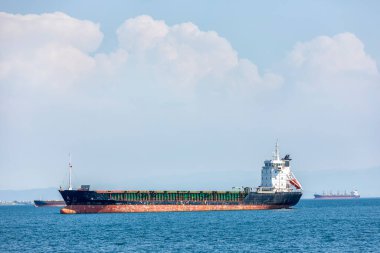 View of the cargo ship and transport for cargo (goods) with blue mediterranean sea and cloudy sky.