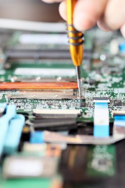 Worker is repairing to inside the laptop. The basic components of laptops function identically to their desktop counterparts. Traditionally they were miniaturized and adapted to mobile use.