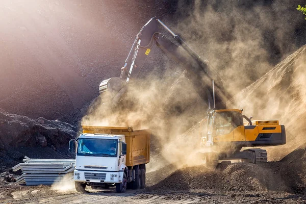 The excavator is digging and loading excavation to dump truck in construction field. Excavators (hydraulic) are heavy construction equipment consisting of a boom, dipper (or stick), bucket and cab.