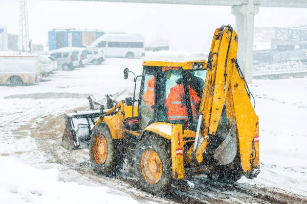 View of a backhoe loader and snowy day in the construction site. It also called a loader backhoe, digger in layman\'s terms, or colloquially shortened to backhoe within the industry.