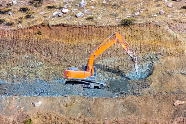 A hydraulic breaker is mounted on the excavator. It is powered by an auxiliary hydraulic system from the excavator, which is fitted with a foot-operated valve for this purpose.