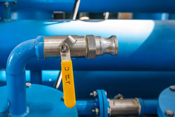 Close-up of a metal pipeline in an industrial area. View of the one inch ball valve with pipe connection. A ball valve is a flow control device which uses a hollow, perforated and pivoting ball to control liquid flowing through it.