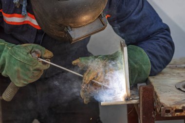 Welder qualification. The welder is welding with shielded metal arc welding process to steel plate in vertical position for welder certification.