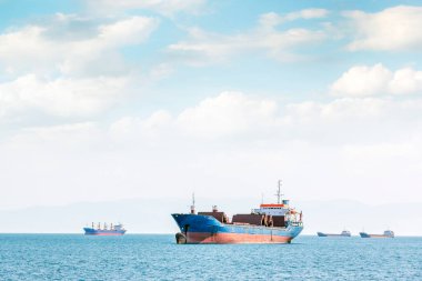 View of the cargo ship and transport for cargo (goods) with blue mediterranean sea and cloudy sky.