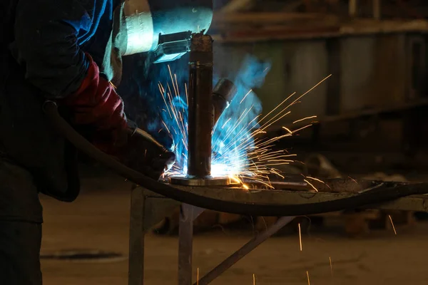 The welder is welding to steel material with gas metal arc welding proces. It sometimes referred to by its subtypes metal inert gas (MIG) welding or metal active gas (MAG) welding.