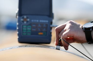 Mühendis, ultrasonik testlerle boru kaynaklarını teftiş edecek. Yansıtılan ultrason, nesnenin arka duvarı gibi bir arayüzden ya da nesnenin içindeki bir kusurdan gelir..