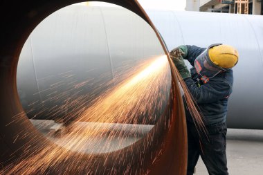 The worker is cutting to metal plate with manual flame cutting process. Oxy-fuel welding, oxyacetylene welding, oxy welding, or gas welding and oxy-fuel cutting are processes that use fuel gases.