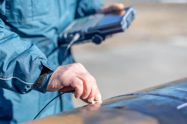 Mühendis, ultrasonik testlerle boru kaynaklarını teftiş edecek. Yansıtılan ultrason, nesnenin arka duvarı gibi bir arayüzden ya da nesnenin içindeki bir kusurdan gelir..