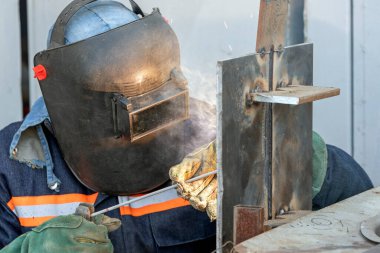 Kaynakçı niteliği. Kaynakçı kaynakçı, kaynakçı sertifikası için çelik plakaya koruyucu metal yay kaynak işlemi yapıyor..