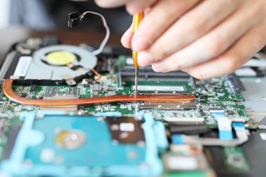 Expert is repairing to inner of laptop with screwdriver. The design restrictions on power, size, and cooling of laptops limit the maximum performance of laptop parts compared.