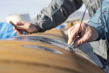 Mühendis, ultrasonik testlerle boru kaynaklarını teftiş edecek. Yansıtılan ultrason, nesnenin arka duvarı gibi bir arayüzden ya da nesnenin içindeki bir kusurdan gelir..