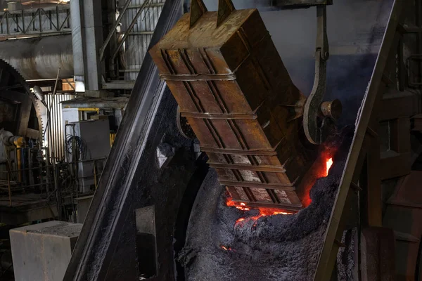 背景に火のついた大きな金属製のオーブン 溶解金属は 工業用鋳造工場の大きな溶融ポットに注ぎます 金属はそれらを液体に溶融し 金型に金属を注ぐことによって形状に鋳造されます — ストック写真