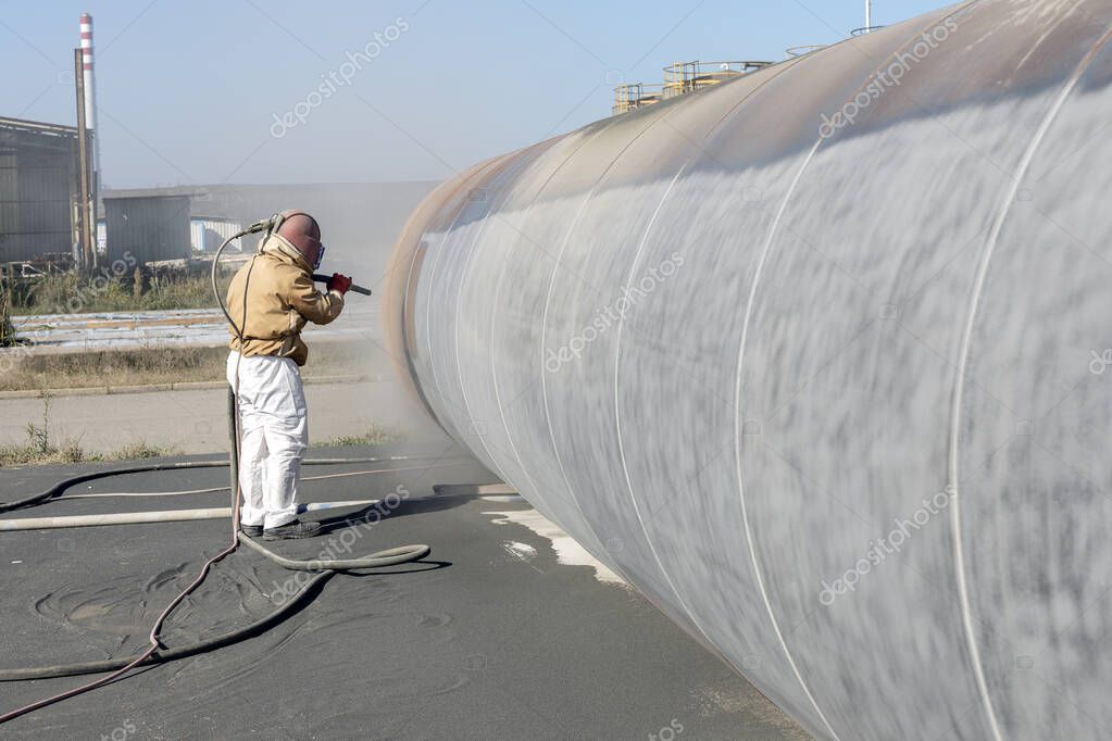 The sandblaster is sanding to steel pipe material. Abrasive blasting