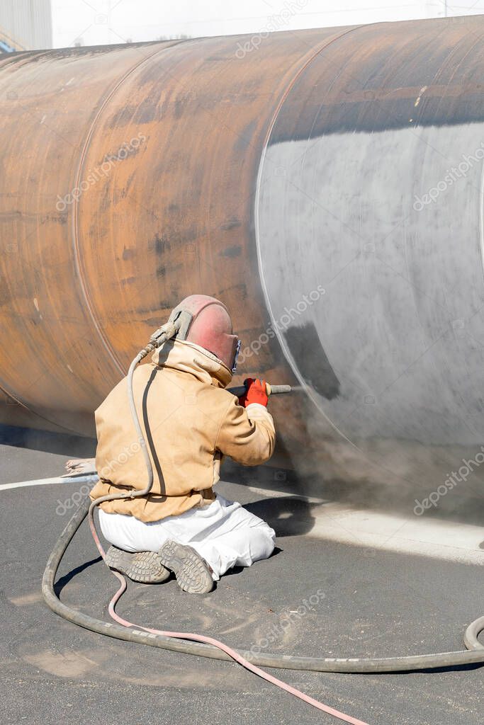 The sandblaster is sanding to steel pipe material. Abrasive blasting