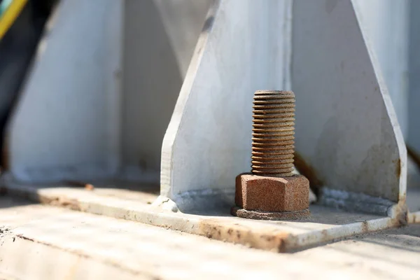 A rusty steel anchor bolt on the flange of the structure steel. Anchor bolts are used to connect structural and non-structural elements to concrete.