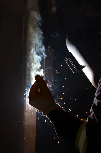 The welder is welding with shielded metal arc welding, manual metal arc welding or stick welding. Electric current is used to strike an arc between the base material and consumable electrode rod.