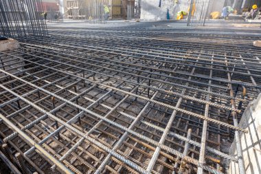 İnşaat alanında güçlendirilmiş beton takviye barı, fotoğrafa yakın çekim. Beton ve yeni bir sanayi tesisi için temelde demir parmaklık kafesleri var. Bağlı bir demiri kafesi. 