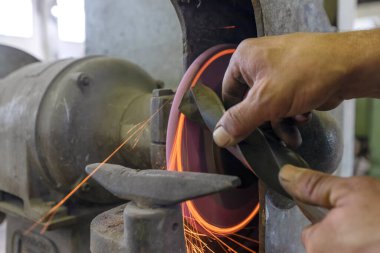 Metal kesmek için öğütücü kullanan bir işçi. Kıyma makinesiyle delmek için öğütülmüş. Kıyma makinesi, ezici tekerlekleri sürmek için kullanılan bir çeşit öğütme makinesidir..