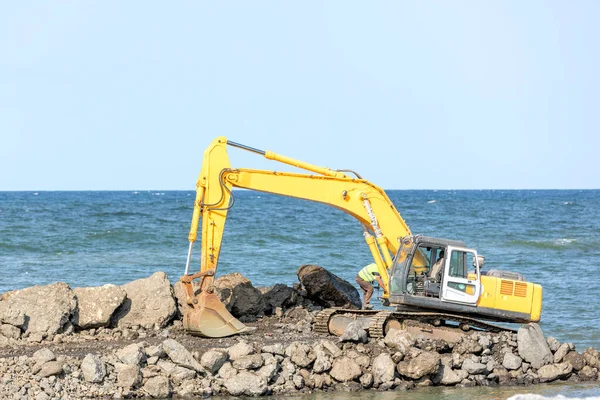 stock image The excavator is working to build pier of harbor in the construction site. Excavators are heavy construction equipment consisting of a boom, dipper (or stick), bucket and cab on a rotating platform.