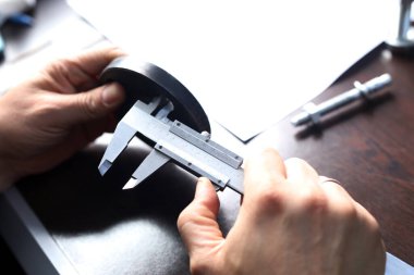 İşçi iç çap delikleri ölçmek için flanş vernier kalibre ile. Vernier kalibreleri yaygın olarak bilimsel laboratuvarlarda ve kalite kontrol imalatında kullanılır..