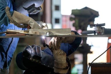 Kaynakçılar paslanmaz çelik levhanın kökünü kurutmak için kaynak yapıyorlar. Fabrikadaki gaz tungsten kavisli kaynak işlemi ile..