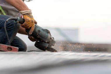 İşçi inşaat alanında çelik malzemelerini öğütüyor..