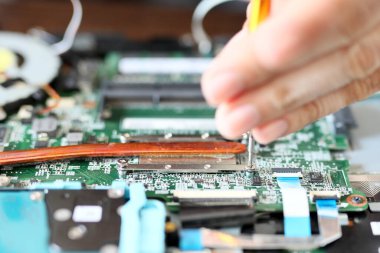 Uzman, dizüstü bilgisayarın içini tornavidayla onarıyor. Dizüstü bilgisayarların güç, boyut ve soğutulmasına yönelik tasarım kısıtlamaları dizüstü bilgisayar parçalarının en yüksek performansını sınırlıyor. Bir bilgisayar donanım mühendisinin yakın çekimi