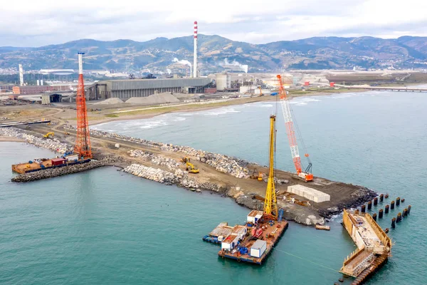 Drone view of a pier construction. A pier is a raised structure that rises above a body of water and usually juts out from its shore, typically supported by piles or pillars, and provides above-water. Aerial view of industrial port.