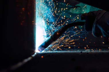 Kaynakçı atölyede gaz metal kaynaklı yapısal bir çelik kaynak yapıyor..