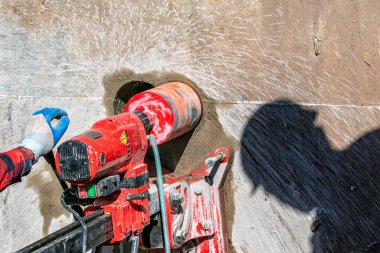 Worker is drilling to concrete wall with core drill machine. Core drills used in metal are called annular cutters. Core drills used for concrete and hard rock generally use industrial diamond grit.
