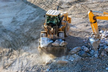 Buldozer olay yerinde çalışıyor. Buldozer ya da dozer, sürekli raylar ya da büyük lastikler üzerinde hareket eden ve ön tarafa malzeme itmek için metal bir bıçakla donatılmış büyük, motorlu bir makinedir..