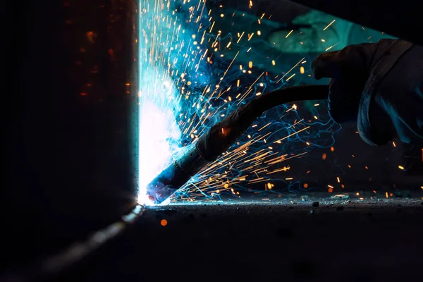 The welder is welding a structural steel with gas metal arc welding ( GMAW ) in the workshop.
