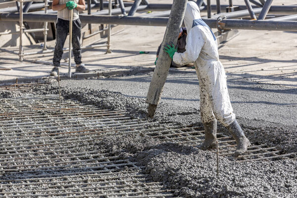 Pouring and smoothing out concrete with ready-mix concrete (RMC) in the construction site. It is concrete that is manufactured in a batch plant, according to a set engineered mix design.