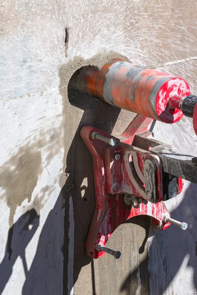 Worker is drilling to concrete wall with core drill machine. Core drills used in metal are called annular cutters. Core drills used for concrete and hard rock generally use industrial diamond grit.
