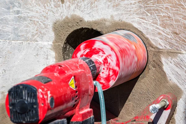 Worker is drilling to concrete wall with core drill machine. core drill is a drill specifically designed to remove a cylinder of material, much like a hole saw. The material left inside the drill bit.