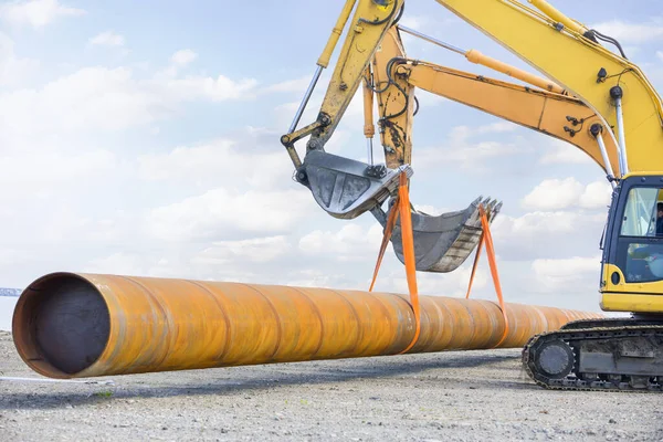 Excavators lift a large pipe together. All movement and functions of a hydraulic excavator are accomplished through the use of hydraulic fluid, with hydraulic cylinders and hydraulic motors.
