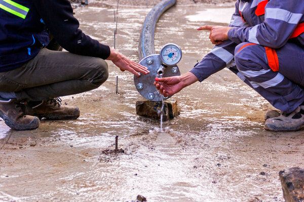 Вид на гидростатические испытания полиэтиленового трубопровода и манометра.