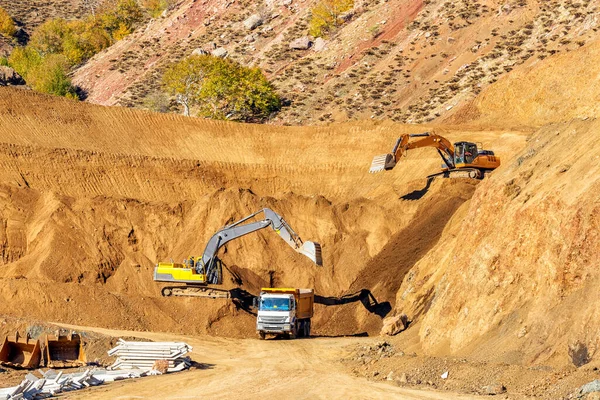 掘削機は建設現場のトラックに土壌を採掘してロードしています — ストック写真