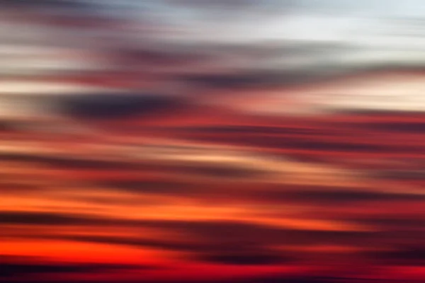 Background of the motion blurry red, white and black clouds under the beautiful sunset sky. Clouds exert numerous influences on Earth\'s troposphere and climate.