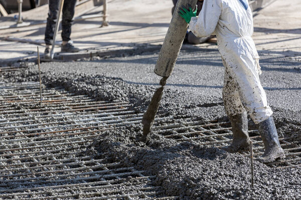 Construction worker is pouring and smoothing out concrete with ready-mix concrete (RMC). It is concrete that is manufactured in a batch plant, according to each specific job requirement.