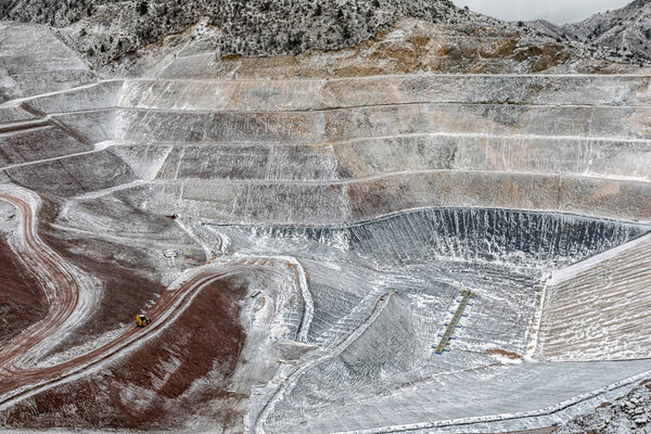 New industrial mine waste dam (tailing dam) with snowy weather. Tailings dams rank among the largest engineered structures on earth. Open pit mine.