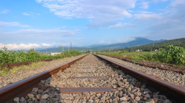 Güneşli bulutlarda tren yolu. Demiryolu sonbahar ormanından geçer..
