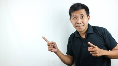 Polo tişörtlü neşeli, pozitif Asyalı genç adam parmaklarını yan yana gösteriyor..